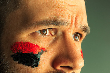 Image showing Portrait of a man with the flag of the Germany painted on him face.