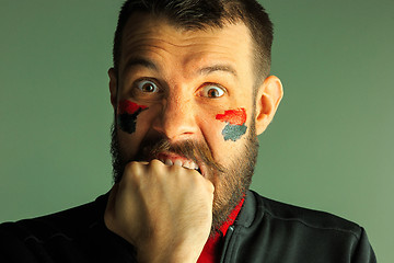 Image showing Portrait of a man with the flag of the Germany painted on him face.