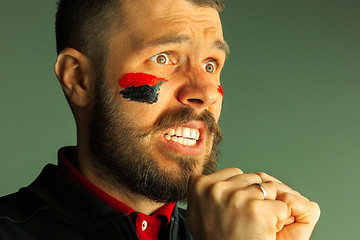 Image showing Portrait of a man with the flag of the Germany painted on him face.