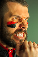 Image showing Portrait of a man with the flag of the Germany painted on him face.