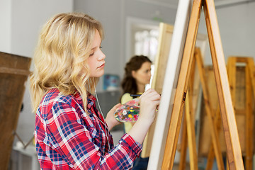 Image showing girl with easel painting at art school studio