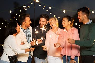 Image showing happy friends with sparklers at rooftop party