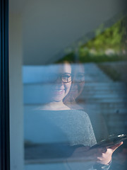 Image showing Woman using tablet at home by the window