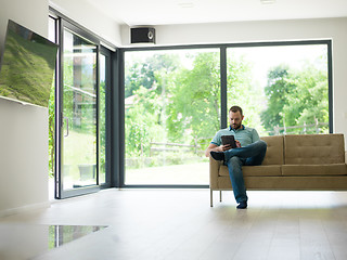 Image showing man on sofa using tablet computer