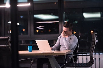 Image showing man working on laptop in dark office