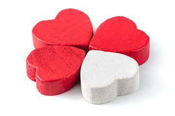 Image showing Three red and one white wooden hearts isolated on white