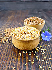 Image showing Flaxen white and brown seed in bowl with flower on dark board