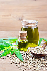 Image showing Oil hemp in two jars on old board