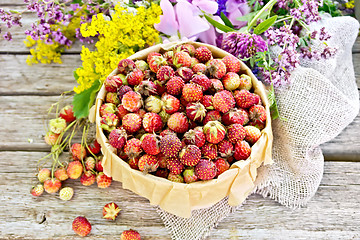 Image showing Strawberries in box with flowers on old board