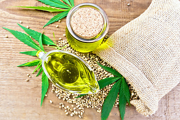 Image showing Oil hemp in sauceboat and jar on board top