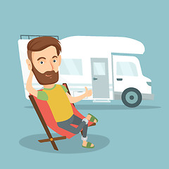 Image showing Man sitting in chair in front of camper van.