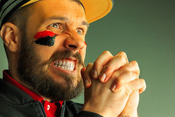 Image showing Portrait of a man with the flag of the Germany painted on him face.