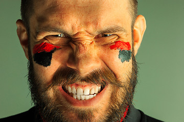 Image showing Portrait of a man with the flag of the Germany painted on him face.