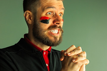 Image showing Portrait of a man with the flag of the Germany painted on him face.