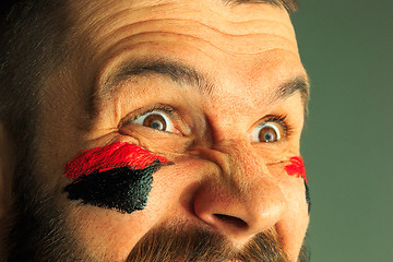 Image showing Portrait of a man with the flag of the Germany painted on him face.