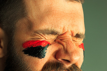 Image showing Portrait of a man with the flag of the Germany painted on him face.