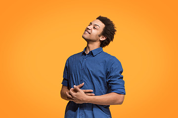 Image showing The happy business man standing and smiling against orange background.