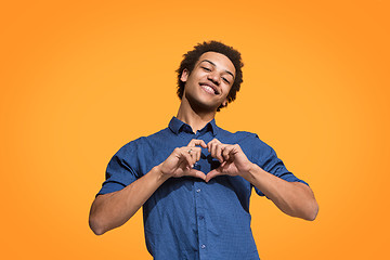 Image showing The happy business man standing and smiling against orange background.