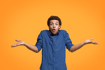 Image showing The young attractive man looking suprised isolated on orange