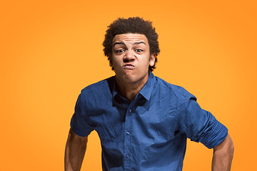 Image showing The young emotional angry man screaming on orange studio background