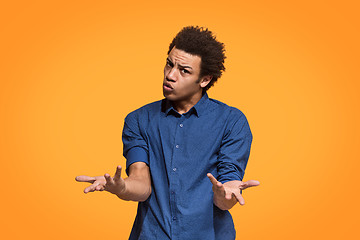 Image showing Beautiful male half-length portrait isolated on orange studio backgroud. The young emotional afro man