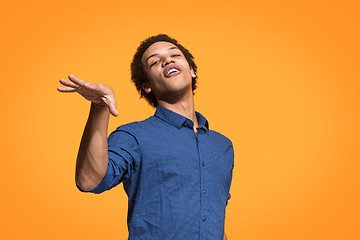 Image showing Beautiful male half-length portrait isolated on orange studio backgroud. The young emotional surprised man