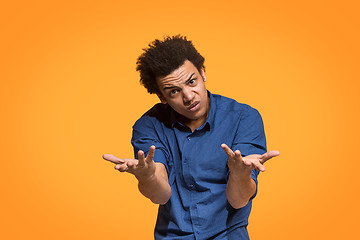 Image showing Beautiful male half-length portrait isolated on orange studio backgroud. The young emotional afro man