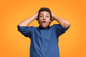 Image showing The young attractive man looking suprised isolated on orange