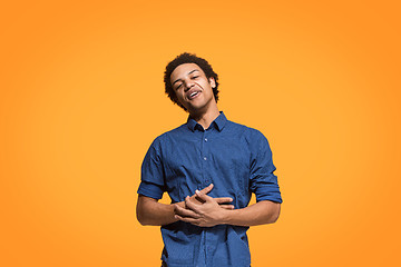 Image showing The happy business man standing and smiling against orange background.