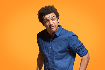 Image showing The young emotional angry man screaming on orange studio background