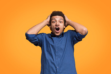 Image showing The young attractive man looking suprised isolated on orange