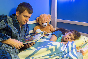 Image showing Dad reads book to daughter at night