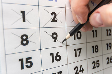Image showing Pencil crosses out dates on the wall calendar