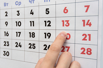 Image showing Hand pointing to the day off Saturday on a wall calendar