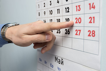 Image showing The office specialist\'s hand points to the day off on the wall calendar