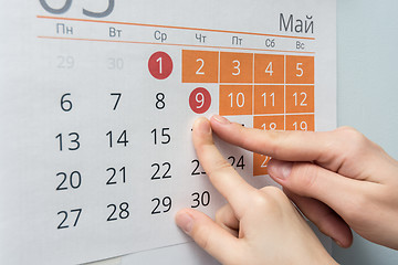 Image showing Child and adult hands indicate the date of May 9 wall calendar