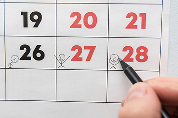 Image showing A pencil draws funny people on a sheet of a wall calendar