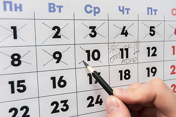 Image showing Hand cross out the last working day with a pencil in the calendar before the holiday