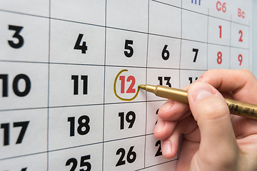 Image showing Hand with a marker on the wall calendar leads around a red holiday