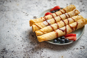 Image showing Plate of delicious crepes roll with fresh fruits and chocolate