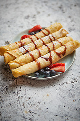 Image showing Plate of delicious crepes roll with fresh fruits and chocolate