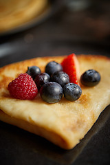 Image showing Close up on pancake with fresh fruit topping placed on dark rusty table