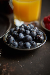 Image showing Close up on fresh blueberries placed on ceramic saucer on dark rusty table