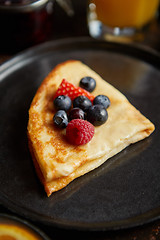 Image showing Tasety homemade pancake on black ceramic plate.