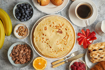 Image showing Breakfast table setting with fresh fruits, pancakes, coffee, croissants