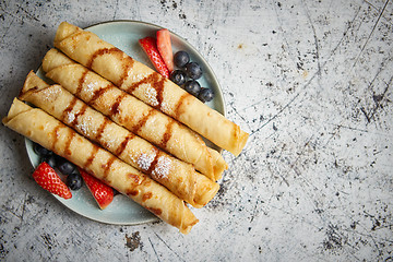 Image showing Plate of delicious crepes roll with fresh fruits and chocolate