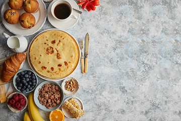 Image showing Breakfast table setting with fresh fruits, pancakes, coffee, cro