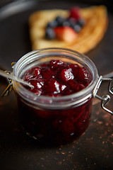 Image showing Close up on jar filled with fresh cherry marmalade placed on dark rusty table