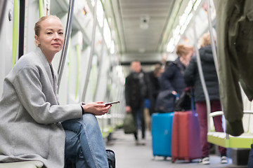 Image showing Beautiful blonde woman using smart phone while traveling by metro public transport.