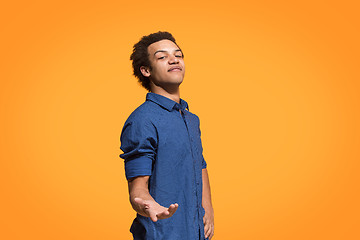 Image showing Beautiful male half-length portrait isolated on orange studio backgroud. The young emotional surprised man